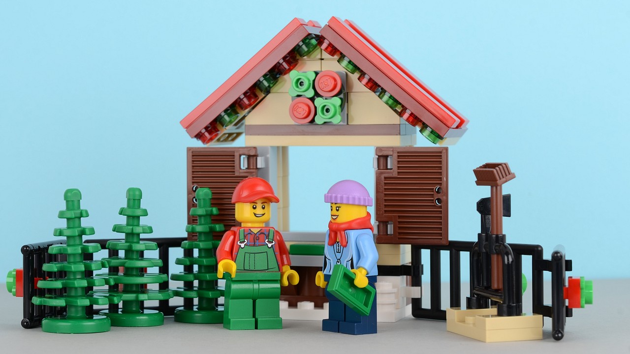 two legos standing outside of a fence and house