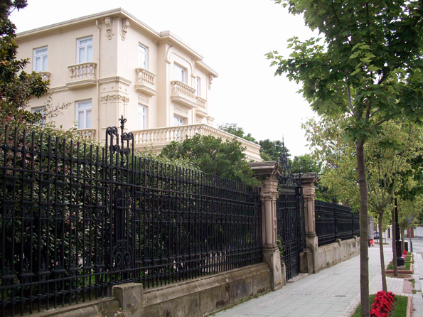 two large buildings are behind the black wrought iron fence