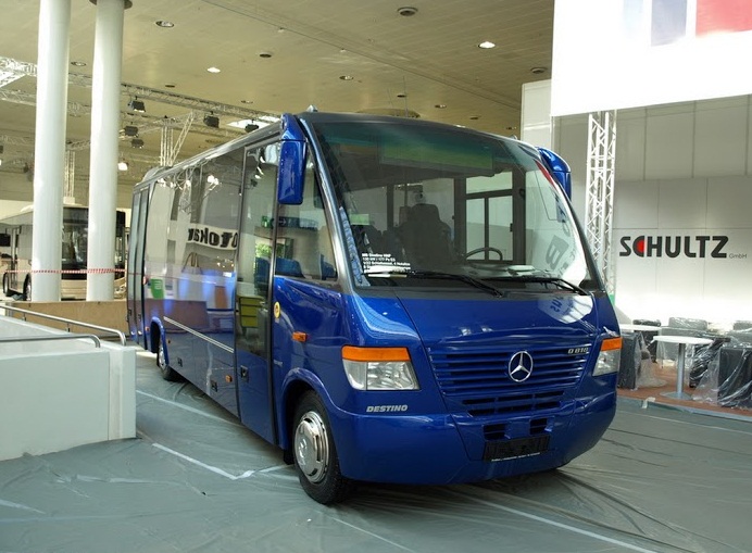 blue mercedes bus on display at an auto show