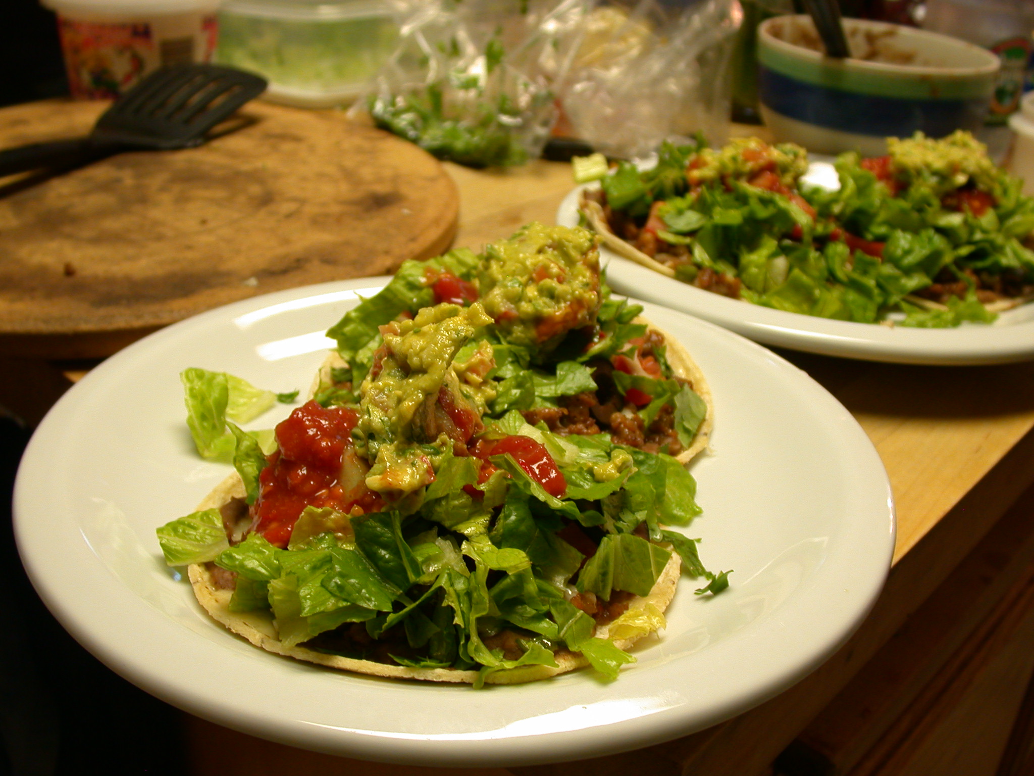 two white plates with tacos and salad on them