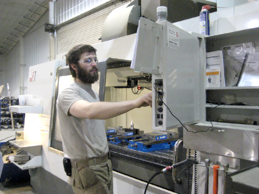 a man in a gray shirt standing by a machine