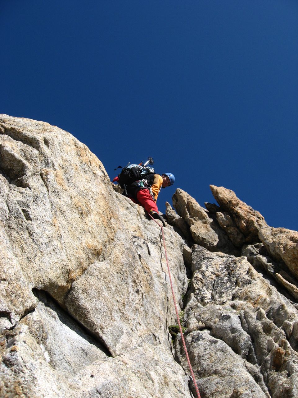 someone climbing a cliff with a backpack and gear