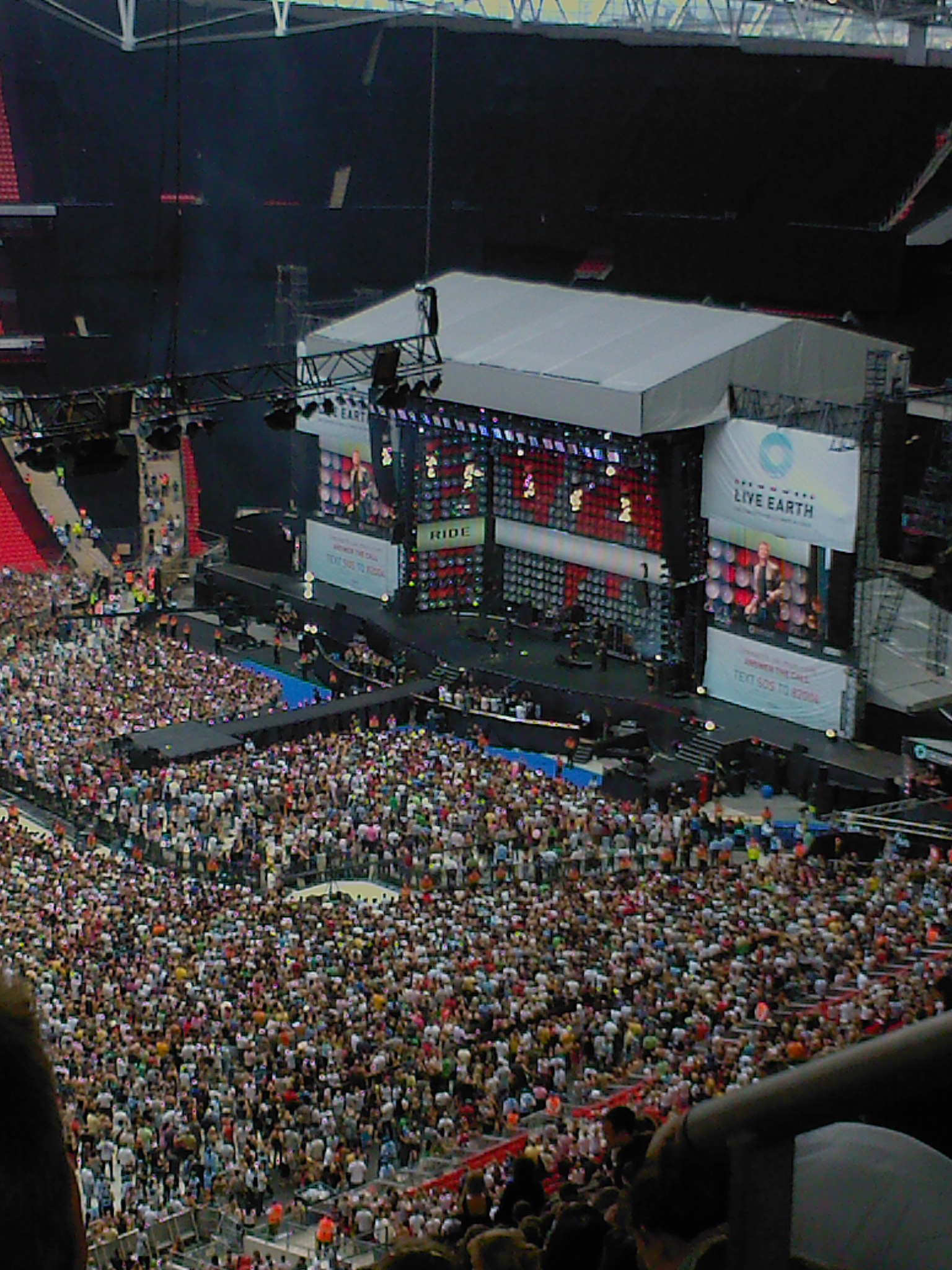 a large crowd of people sitting at a stage watching a concert