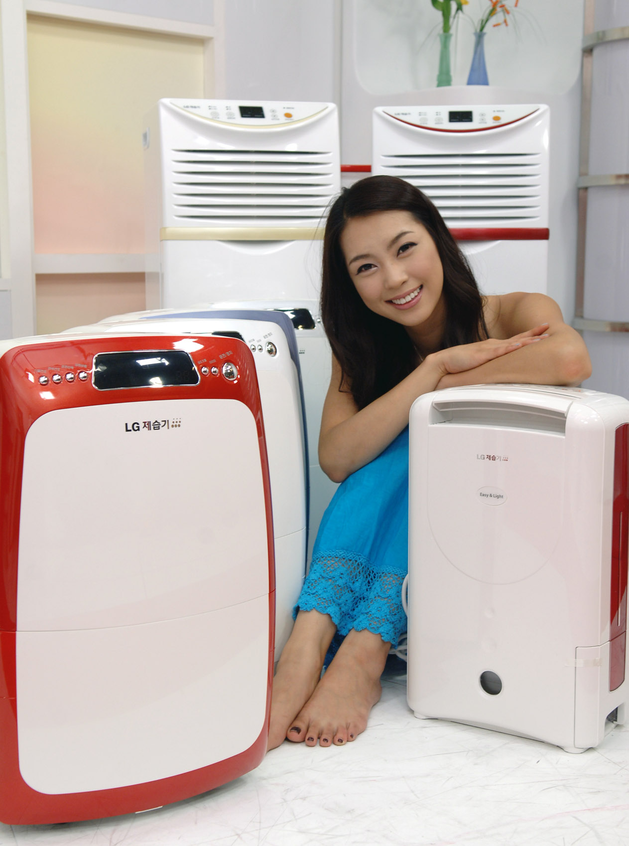 a pretty young woman sitting next to a refrigerator