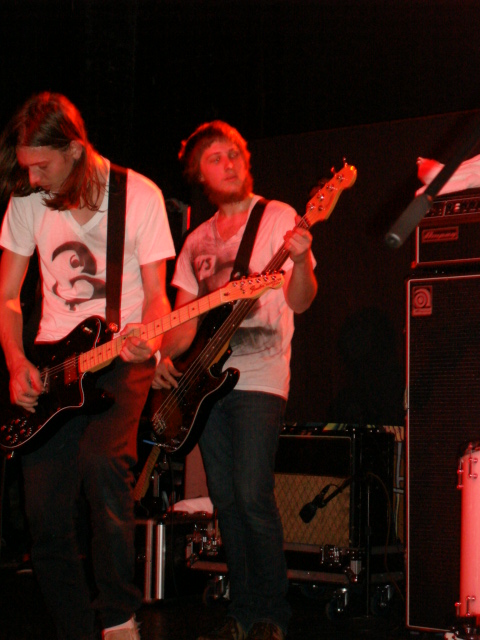 two guys are playing guitars on stage at a party