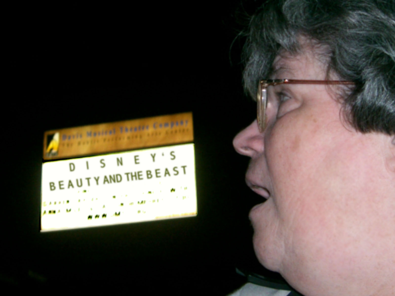 a woman talking while looking at a sign in the dark