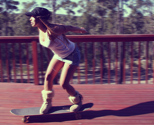girl skating on a wooden deck while looking over the railing