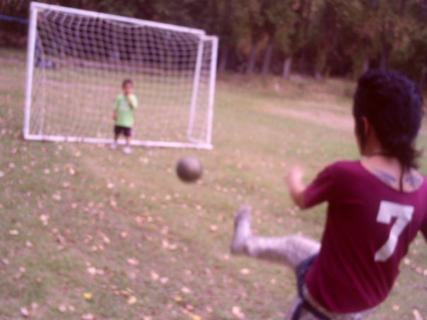 a girl kicking a soccer ball towards an open goal