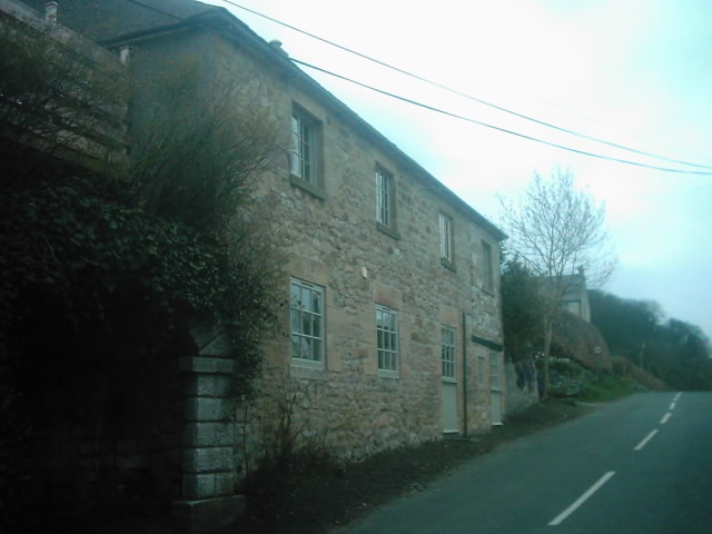 two brick buildings are along a narrow country road