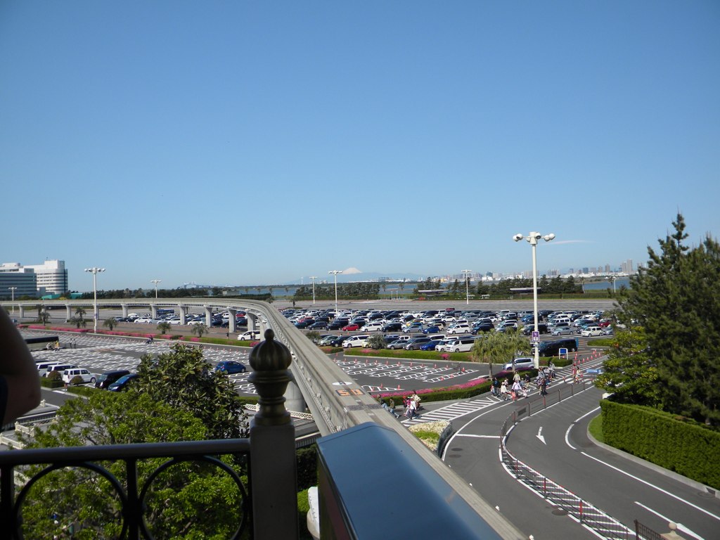 cars on an overpass with buildings and a parking lot next to it