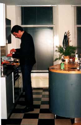 a man is standing in a kitchen by a table