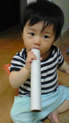 a baby sitting on the floor holding an empty toilet paper