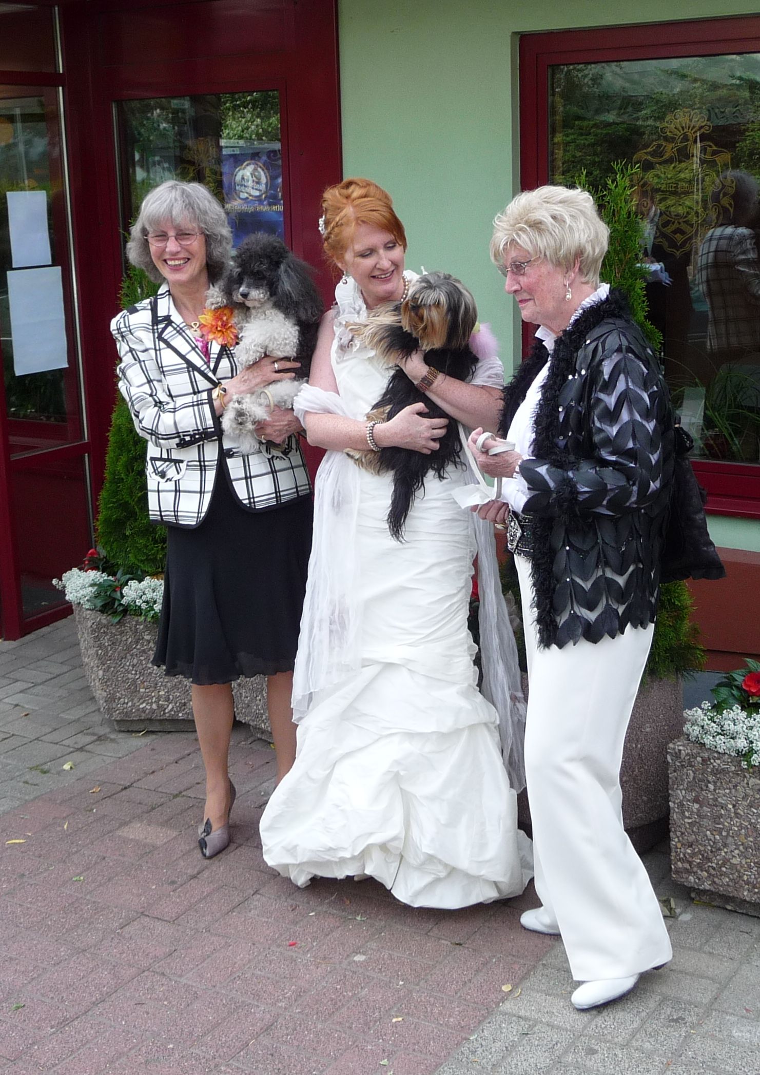 two women are holding a little dog outside