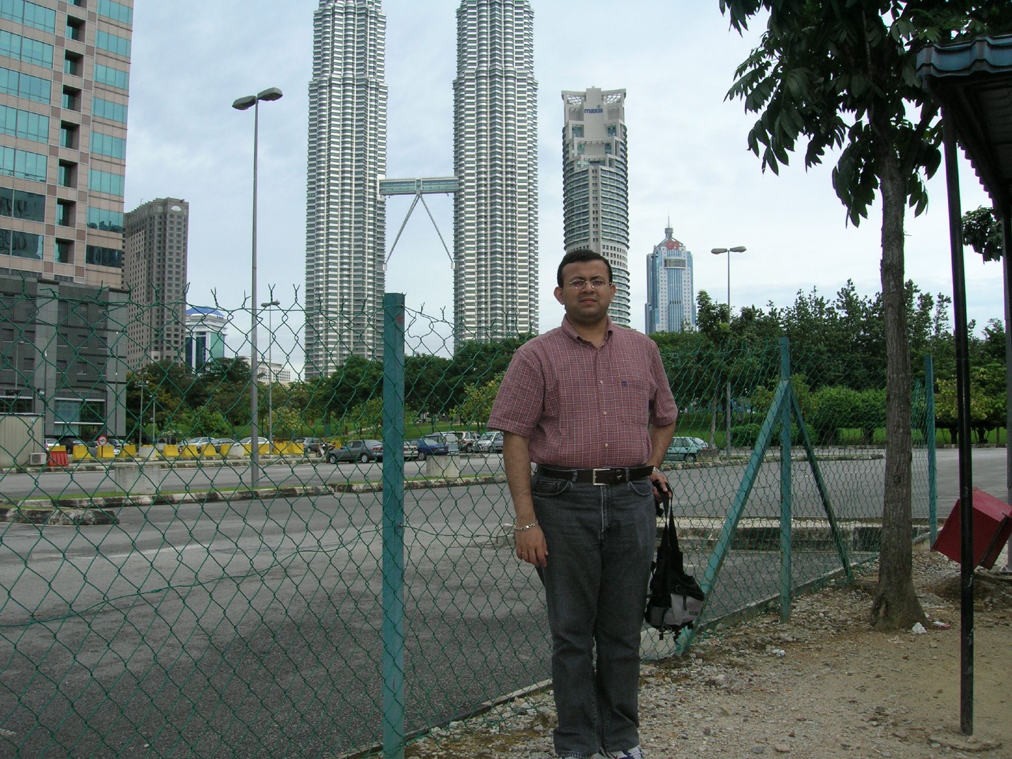 a man stands outside in front of a fence and buildings