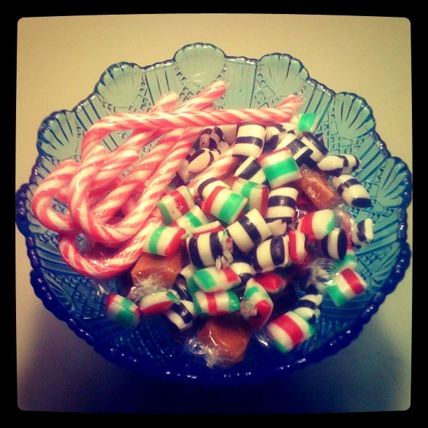 a blue bowl filled with candy canes on top of a table
