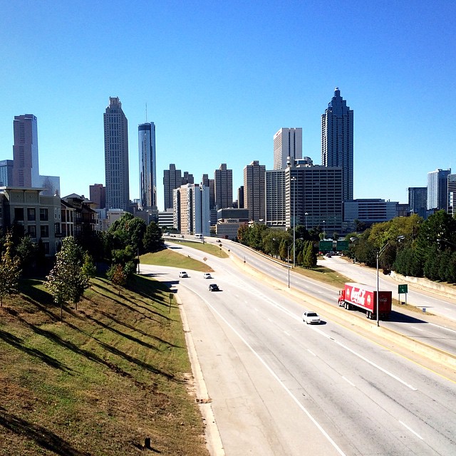 vehicles drive on an empty highway with skyscrs in the background