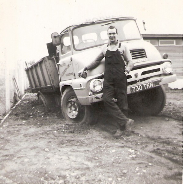 an old black and white po shows a worker in front of a truck