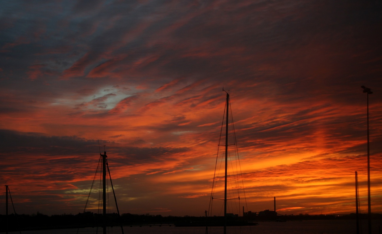 some sail boats sit in the water and one is setting