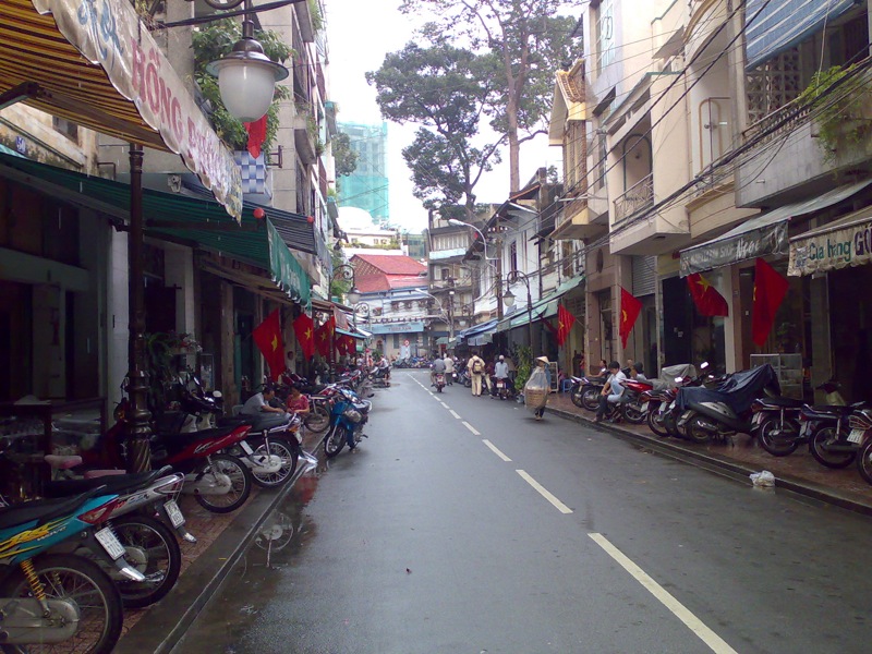 a narrow city street with lots of motorcycles parked near the sidewalks