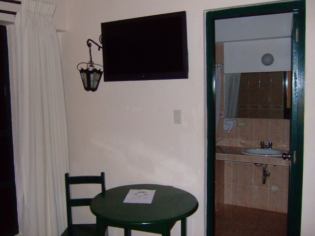 a television on the wall next to the table with a small chair