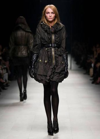 there is a woman wearing a coat and shoes on the runway