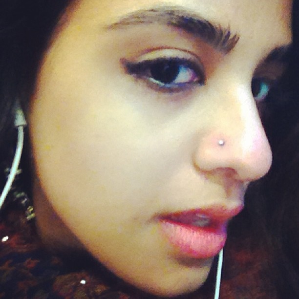an asian woman has her nose pierced up with some piercings