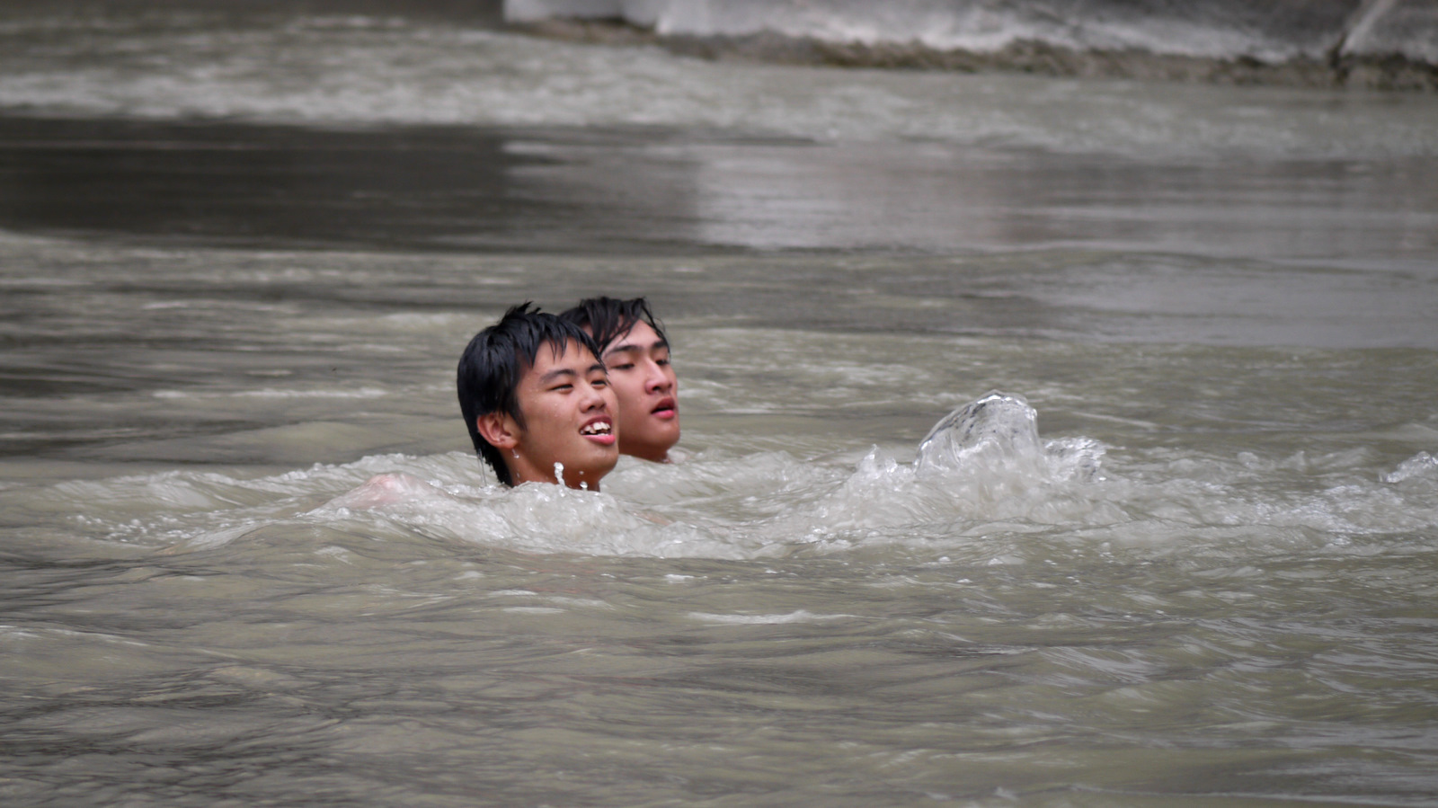 two children swim in the river, one with his face in the water