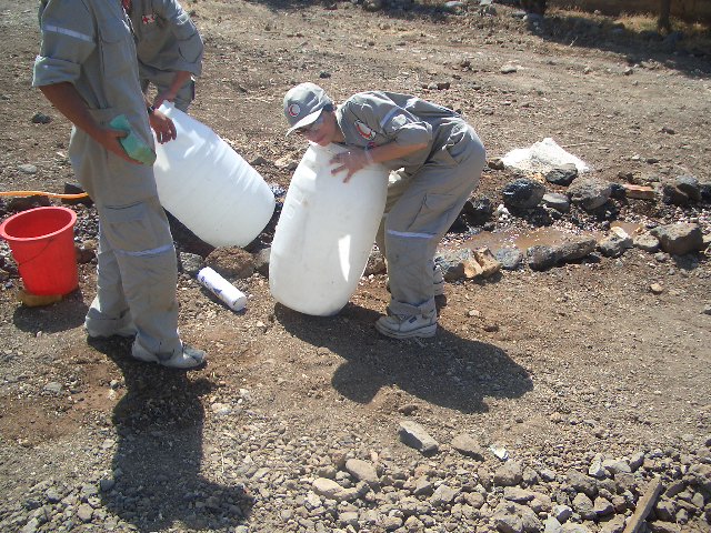 a man is holding a jug while another person kneels down