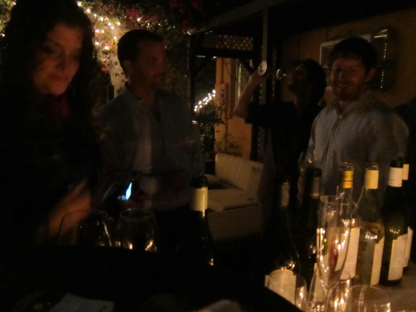 a group of people stand in front of bottles of wine