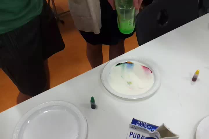 a table with paint on it and someone placing a plastic bottle in the center