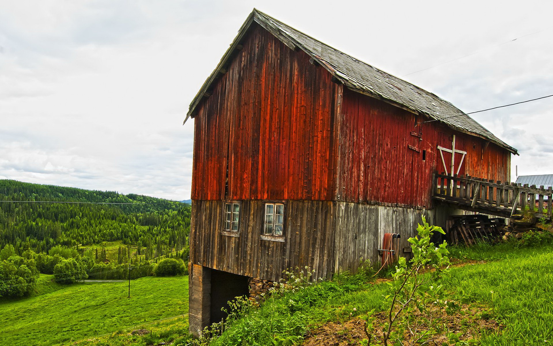 a red barn sits on the side of a hill