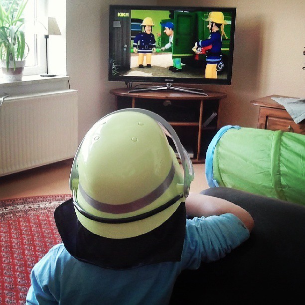 a person wearing a helmet watching television in a living room