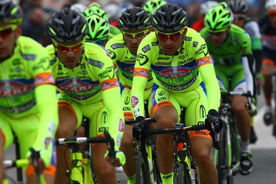 several men are riding bikes and one of them has a helmet on