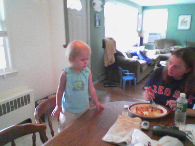 a small child standing in front of a pan filled with food