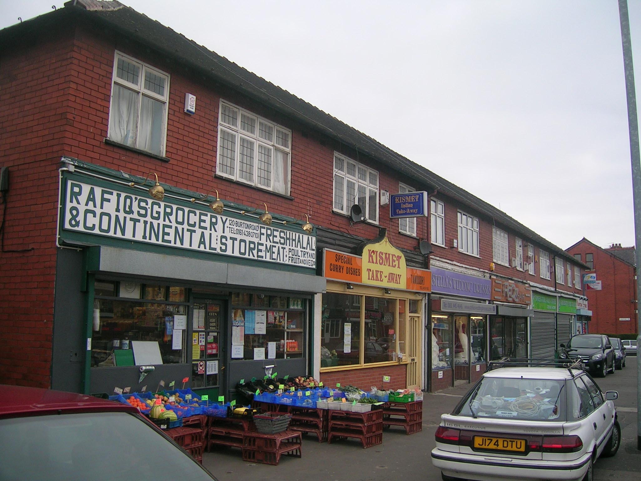 several stores near a parking lot with a car parked in front