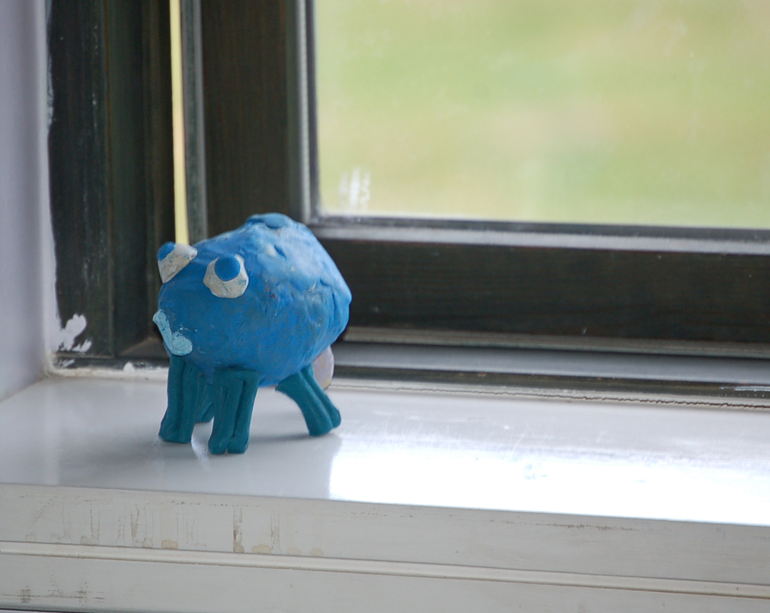 a blue animal is sitting in front of a window