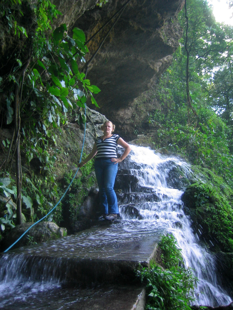 a woman is standing next to a small waterfall