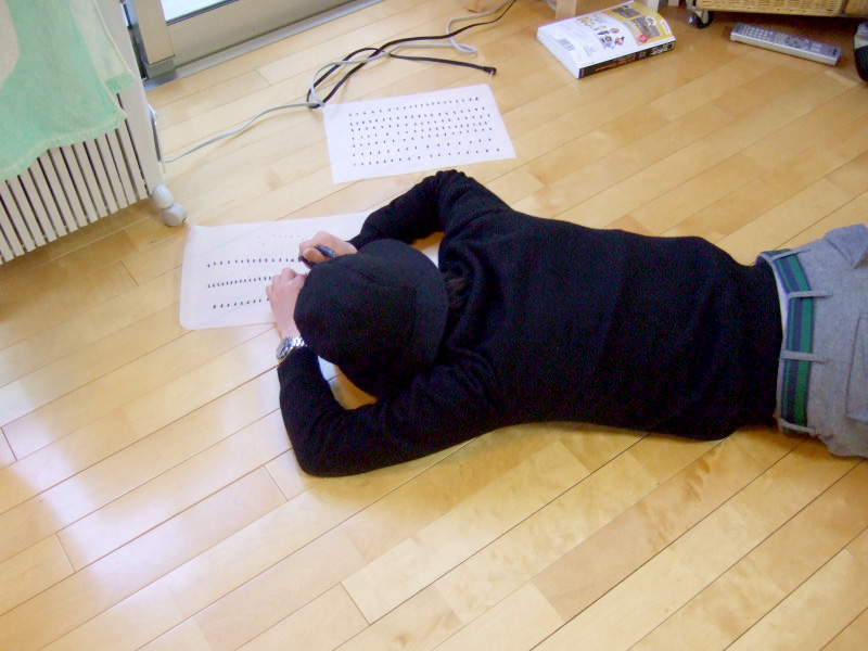 a young person lying on the floor writing in sheets
