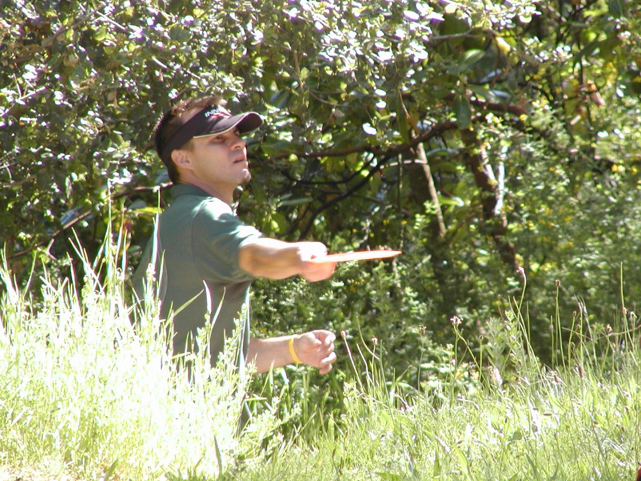 a man holding soing in the grass near trees