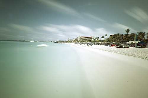 a beach with palm trees and buildings on both sides