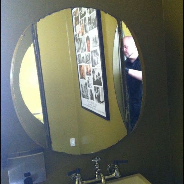 this bathroom sink has an oval mirror and gold wall