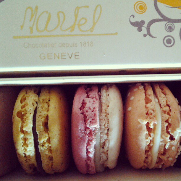 three different colored macaroons are in a box