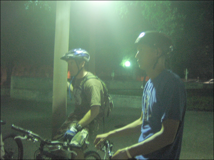 two people standing next to a lamp and bicycle