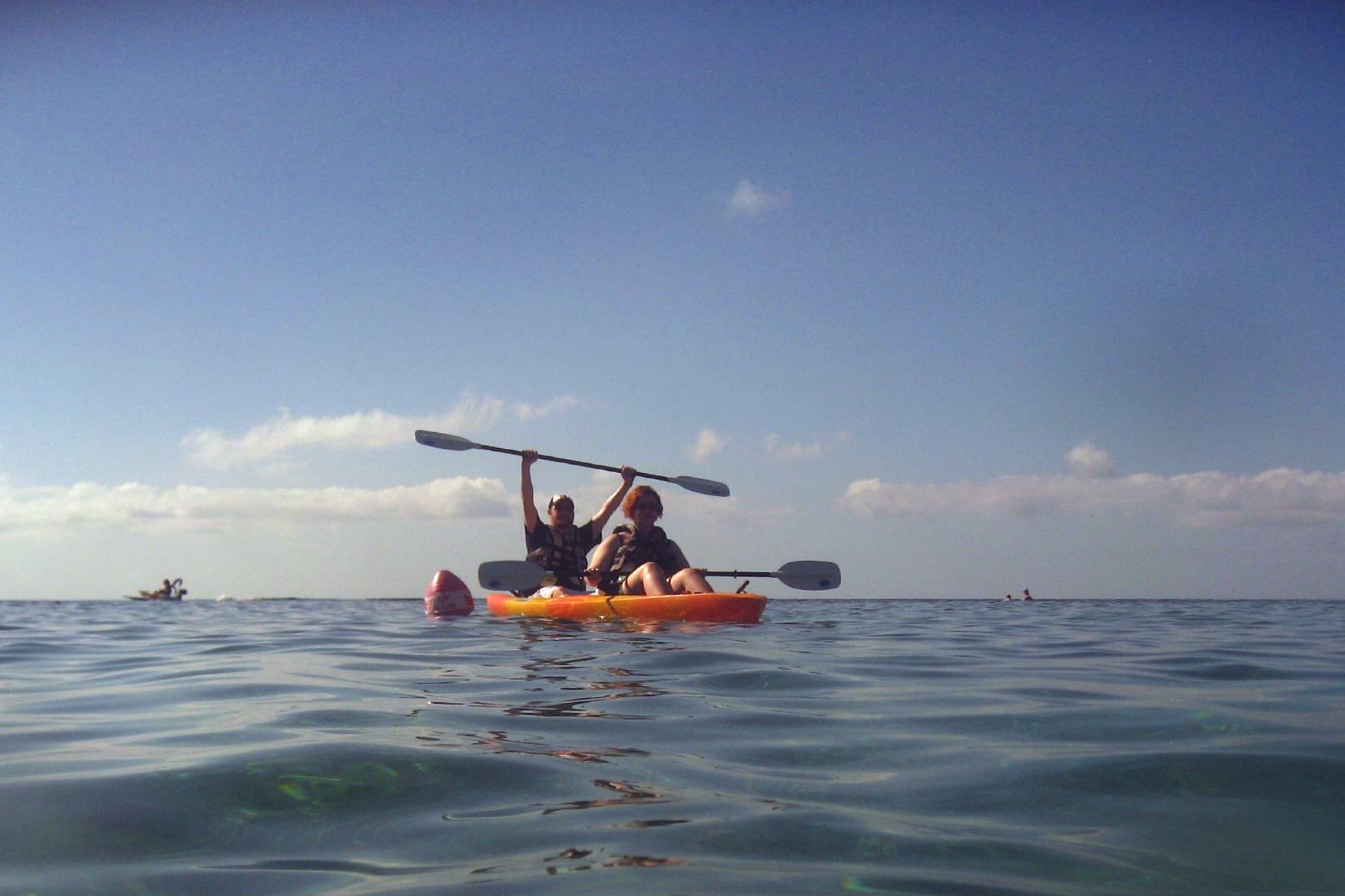 two people paddle a small boat on the open water