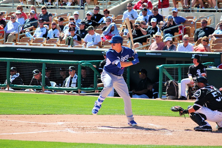 a baseball player runs towards a base while the batter takes a swing