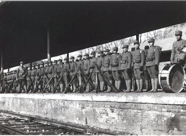 black and white pograph of soldiers standing near a train
