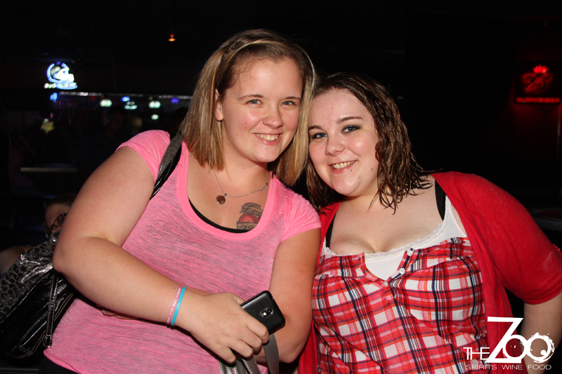 two women standing next to each other and one holding a cell phone