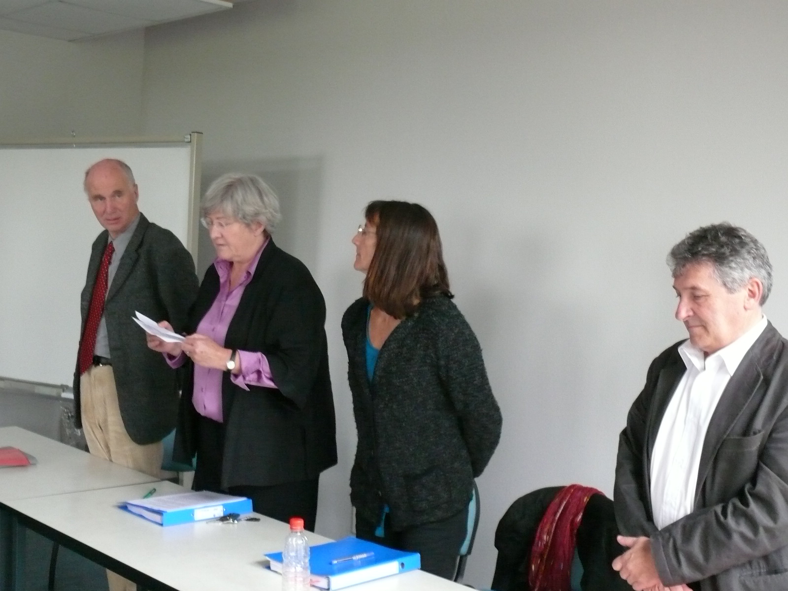 four people stand in front of a meeting table