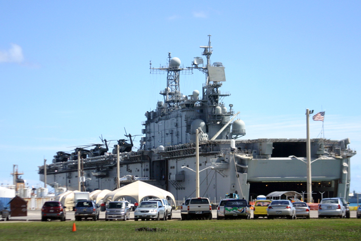 there is a very large battleship and a lot of cars parked next to it