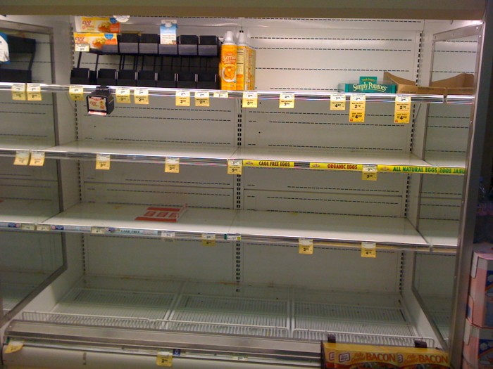 empty shelves with boxes of cheese in a supermarket